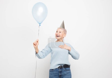 Téléchargez les photos : Portrait of her she nice-looking attractive lovely overjoyed cheerful cheery gray-haired lady holding blue balloon, surprised, rejoices presses his hand to his chest - en image libre de droit