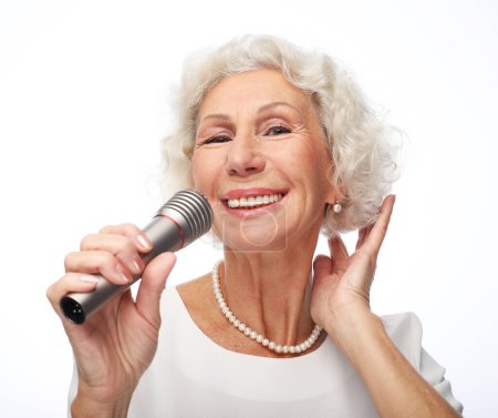 Photo for Emotion, lifestyle and old people concept: Happy senior woman with curly hair singing with microphone, having fun, expressing musical talent - Royalty Free Image