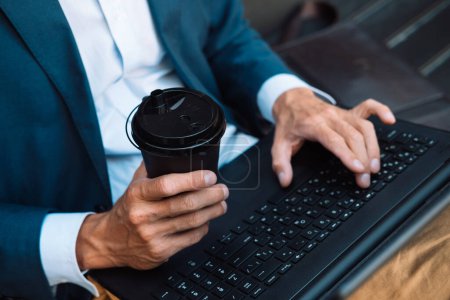 Photo for Close up young businessman holding his laptop and coffee to go. Outdoor portrait. - Royalty Free Image
