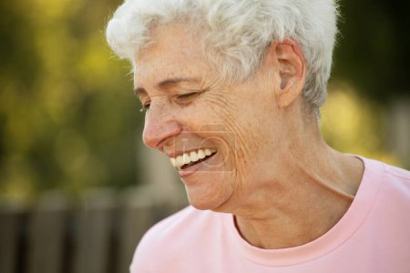 Foto de The old woman laughs with her eyes closed. Positive mood. Happy old age. Close up Portrait in the park. - Imagen libre de derechos