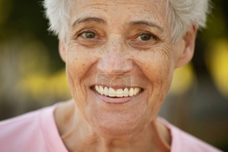 Téléchargez les photos : Portrait of smiling elderly woman at park. Close up portrait. Happy thoughful mature woman relaxing outdoor. Old active retired woman. - en image libre de droit