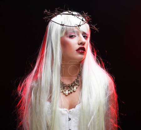 Téléchargez les photos : Une jeune femme avec un maquillage lumineux et de longs cheveux blancs avec une couronne en fil de fer. Concept de fête et de carnaval. - en image libre de droit