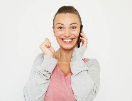 Téléchargez les photos : Jeune femme heureuse parlant dans son téléphone portable sur fond blanc - en image libre de droit