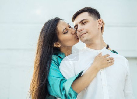 Photo for A young happy loving couple of different nationalities are hugging on the embankment against the background of water.Asian woman and European man. Happy summer time. - Royalty Free Image