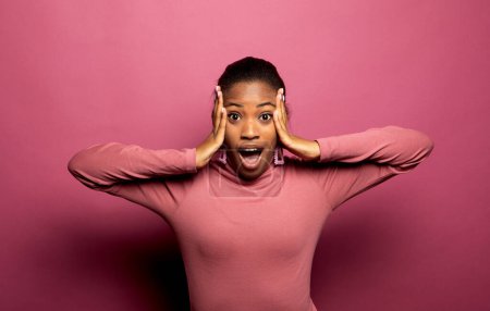 Photo for Young African American female stares at camera and keeps mouth opened, scratches head and looks surprisingly, realizes bad news, stands against pink background. People, reaction, ethnicity concept, - Royalty Free Image