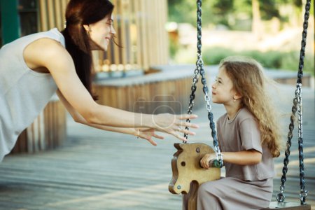Photo for Portrait of enjoy happy love mother with little child girl smiling playing and pushing daughter on the swing moments good time in park. Lifestyle and family concept. - Royalty Free Image