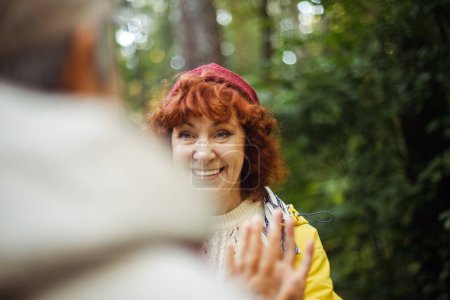 Photo for Happy senior couple women looking at each other walking in the forest holding hands. Caucasian active elderly gray haired people enjoying vacation freedom and nature hiking in footpath in a sunny day - Royalty Free Image