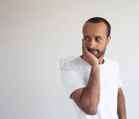 Foto de Hombre afroamericano joven con camiseta blanca tocando la boca con la mano con expresión dolorosa debido a dolor de muelas o enfermedad dental en los dientes. - Imagen libre de derechos