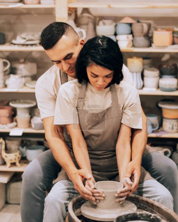 Téléchargez les photos : Couple in love working together on potter wheel in craft studio workshop. Lifestyle cocnept. - en image libre de droit