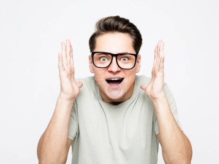Photo for Lifestyle, emotion and people concept: Shocked amazed surprised man wear eyeglasses standing keeping mouth open spreading hands over white background - Royalty Free Image