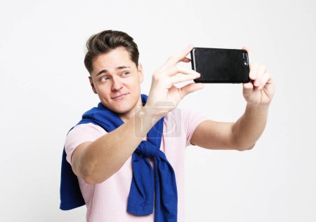 Photo for Lifestyle, tehnology and old people concept. Portrait of a handsome young man taking a selfie isolated over white background - Royalty Free Image
