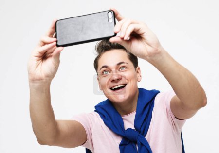 Téléchargez les photos : Lifestyle, tehnology and old people concept. Portrait of a handsome young man taking a selfie isolated over white background - en image libre de droit