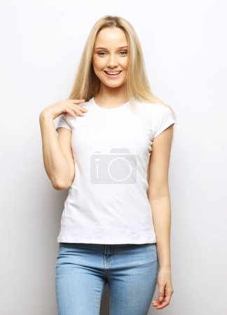 Photo for Attractive excited young blond woman wearing casual clothing standing isolated over white background, looking at camera - Royalty Free Image