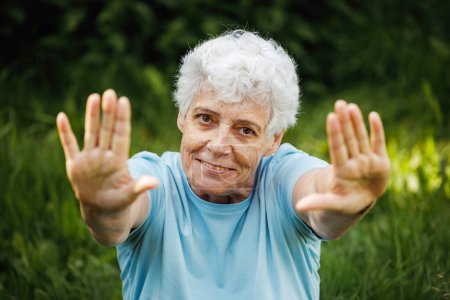 Photo for Mature woman relaxing in nature. Old woman meditating. Senior woman is doing yoga in the park. Smiling aged lady exercising. Old female workout. Sport training. Rehabilitation. Elderly woman. Citizen - Royalty Free Image