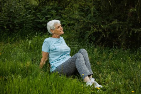 Photo for Mature woman relaxing in nature. Old woman meditating. Senior woman is doing yoga in the park. Smiling aged lady exercising. concepts about elderly, seniority and wellness aging - Royalty Free Image