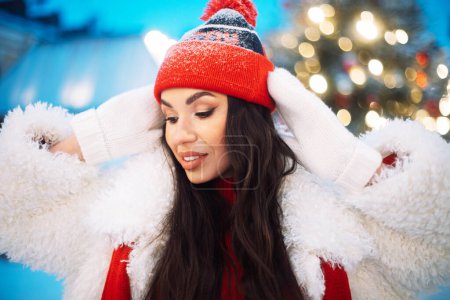 Photo for Charming young woman at the Christmas market next to the New Year tree. Lifestyle concept. - Royalty Free Image