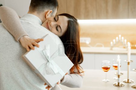 Téléchargez les photos : Happy young woman embracing loving husband, feeling thankful for getting present in wrapped gift box, celebrating happy birthday or marriage anniversary, international women s day. - en image libre de droit