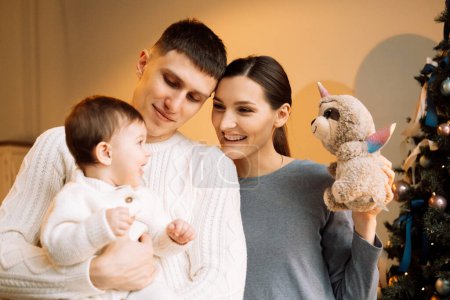 Téléchargez les photos : Happy father standing near wife holding cute little daughter, christmas and family concept - en image libre de droit