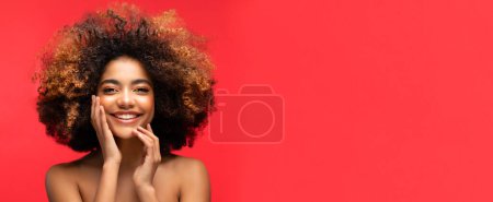 Foto de Estilo de vida, emoción y concepto de la gente: Joven hermosa mujer afroamericana con el pelo afro sonriendo y sintiéndose feliz. Primer plano Retrato sobre fondo rojo. - Imagen libre de derechos