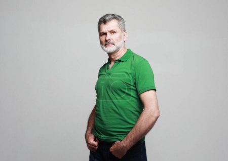Téléchargez les photos : Portrait of senior elderly caucasian old man wearing green t-shirt isolated on grey color background. - en image libre de droit