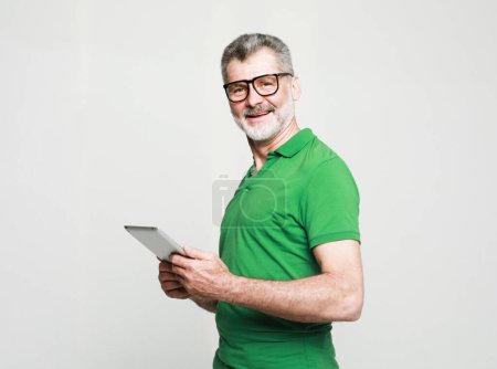 Photo for Lifestyle, tehnology and people concept: Happy senior man using digital tablet. Studio shoot over grey background - Royalty Free Image