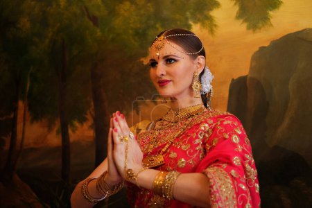 Photo for Young woman in red sari, traditional Indian bride, hands folded, namaste, close up - Royalty Free Image