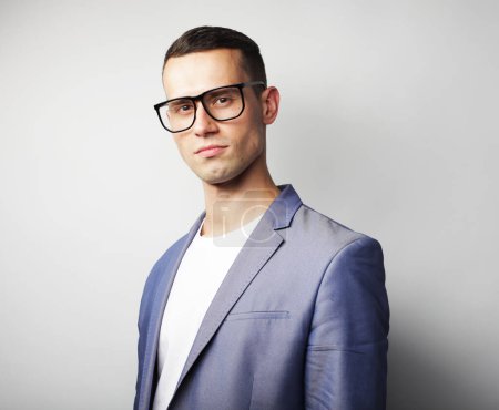 Foto de Portrait of young handsome fashionable man wearing glasses over grey background - Imagen libre de derechos