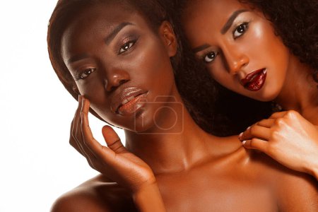 Téléchargez les photos : Glamour beauty. Two beautiful african women with bright make up posing in front of a white background with bare shoulders. - en image libre de droit
