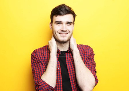 Téléchargez les photos : Lifestyle and people concept: Portrait of young smiling man standing against yellow background - en image libre de droit