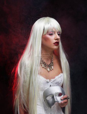 Téléchargez les photos : Party and fashion concept: Beautiful young woman with long white hair holding a silver carnival mask - en image libre de droit