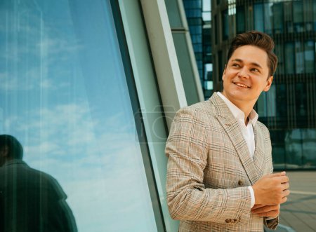 Photo for Young and successful. Handsome young businessman while walking outdoors with office building in the background. Summer day. - Royalty Free Image