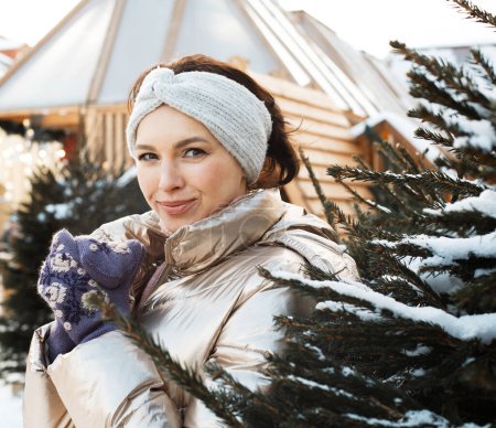Foto de Young woman in winter clothes next to the Christmas tree, winter, christmas market. - Imagen libre de derechos
