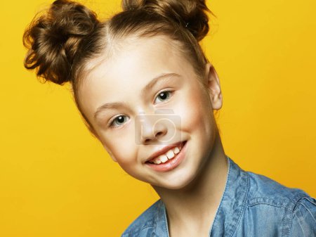 Photo for Close up of funny little girl with blonde curly hair laughing,looking in camera with satisfied expression over yellow background - Royalty Free Image