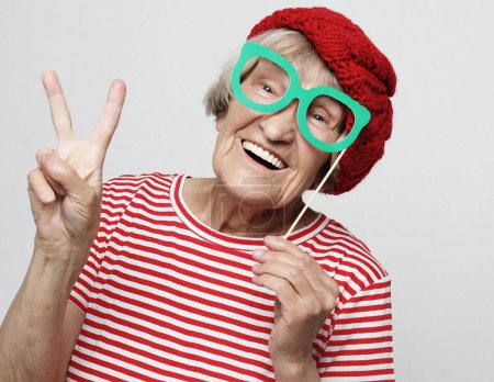 Photo for Lifestyle, emotion and people concept: funny grandmother with fake glasses, laughs and ready for party, over grey background - Royalty Free Image