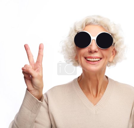 Foto de Estilo de vida, emoción y concepto de personas: Mujer mayor con gafas de sol grandes haciendo acción funky aislado sobre fondo blanco - Imagen libre de derechos