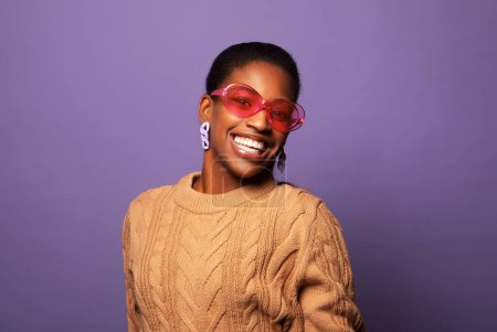 Photo for Blithesome african woman in sunglasses chilling during photoshoot. Indoor shot of adorable black girl in pink glasses over purple background. - Royalty Free Image