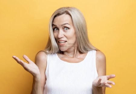 Téléchargez les photos : Old people, modern lifestyle, body language concept. Close-up portrait of shocked mature woman with long white hair, looking at camera, isolated on yellow background - en image libre de droit
