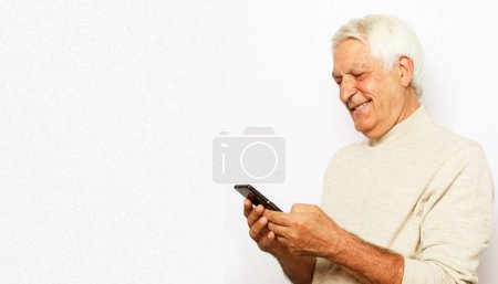 Téléchargez les photos : Tehnology et concept de personnes âgées : Portrait de l'homme âgé qui est la messagerie sur smartphone sur fond blanc, gros plan - en image libre de droit