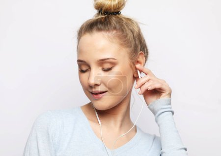 Foto de Beautiful young woman with closed eyes in headphones listening to music over white background - Imagen libre de derechos
