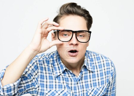 Foto de Young man wearing blue casual plaid shirt clothes and glasses surprised and shocked with excited face over white background - Imagen libre de derechos