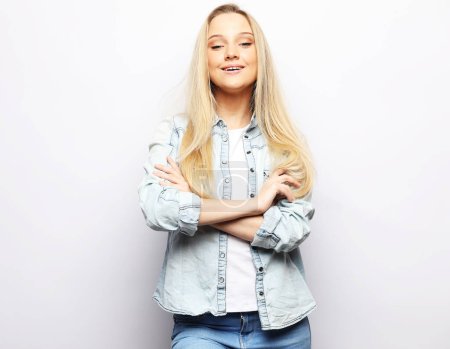 Foto de Young cheerful blonde woman with crossed arms, smiling and looking at the camera over white background - Imagen libre de derechos