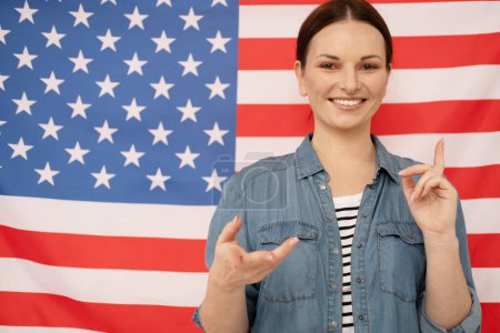 Photo for Young beautiful english teacher smiling and posing against american flag background - Royalty Free Image