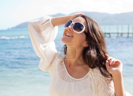 Foto de Young woman with sunglasses on summer beach, happy vacation - Imagen libre de derechos