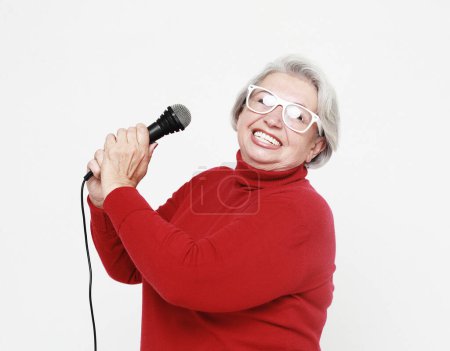 Photo for Emotion, lifestyle and old people concept: Happy senior woman singing with microphone, having fun, expressing musical talent over white background - Royalty Free Image
