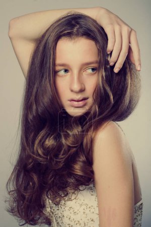 Téléchargez les photos : Fashion, beauty and people concept: lovely young woman with long wavy hair in a white dress touches her hair - en image libre de droit