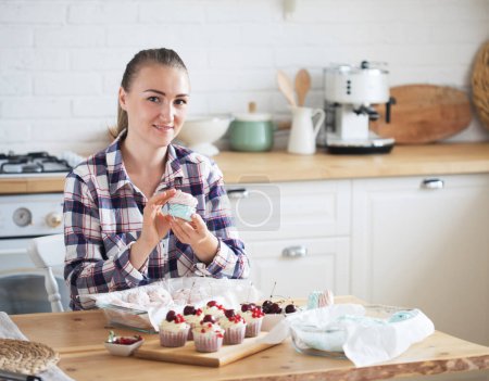 Téléchargez les photos : Beautiful woman pastry chef makes sweet cakes in kitchen. Lifestyle concept. - en image libre de droit