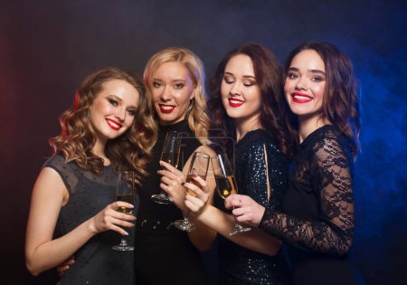 Photo for Group of happy partying women clinking flutes with sparkling wine over blue background - Royalty Free Image