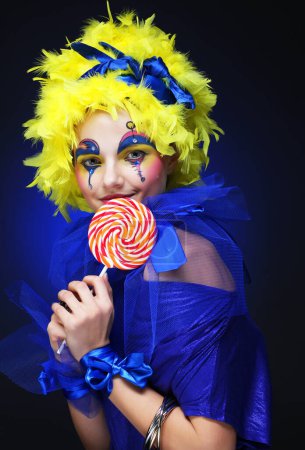 Téléchargez les photos : Jeune femme au visage créatif avec sucette. Fête et carnaval. Brillante perruque. Gros plan. - en image libre de droit