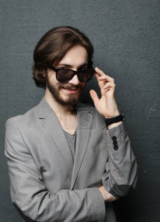 Foto de Portrait of a young handsome man wearing sunglasses on grey background. Studio fashion portrait. - Imagen libre de derechos