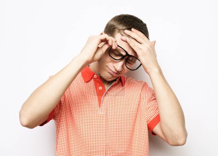Foto de Young handsome man wearing eyeglasses with hand on head for pain in head because stress. Isolated on white background. - Imagen libre de derechos